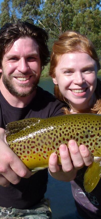 A happy couple Young couple holding big brown trout