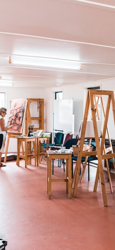 Several easels holding large canvases are set up in a large room.