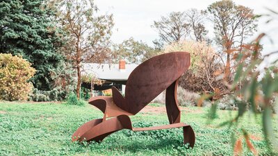 An abstract steel sculpture of geometric forms with a rusty patina in the garden.