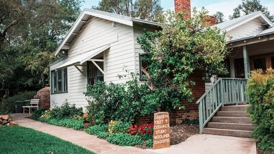 A white weatherboard house surrounded by gardens.