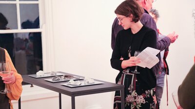 A woman looks at a plinth supporting ceramic artworks.