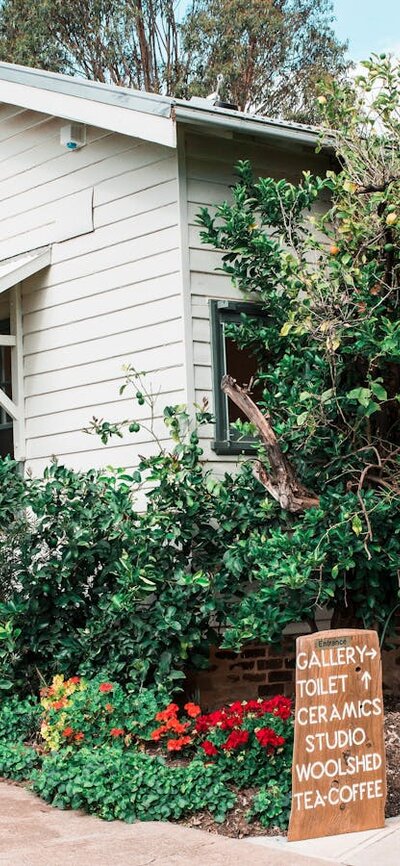 The Homestead at Strathnairn houses galleries, the shop and the cafe. A white weatherboard house surrounded by gardens.