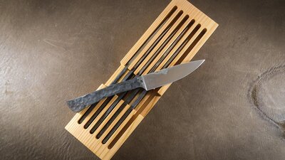 rustic hand forged steak knives atop wooden box