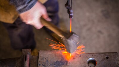 blacksmith striking hot metal on an anvil with sparks flying