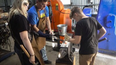 Man and children blacksmithing on an anvil