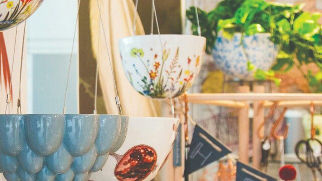 Grey ceramic jelly mould hanging planter in the foreground with botanical print ceramic hanging ...