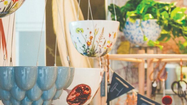 Grey ceramic jelly mould hanging planter in the foreground with botanical print ceramic hanging ...