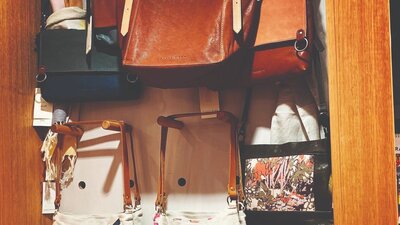 Leather handbags hanging on a pegboard display with printed linen totes