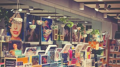 Posters of portraits from collection in the background with rows of boxed stationery