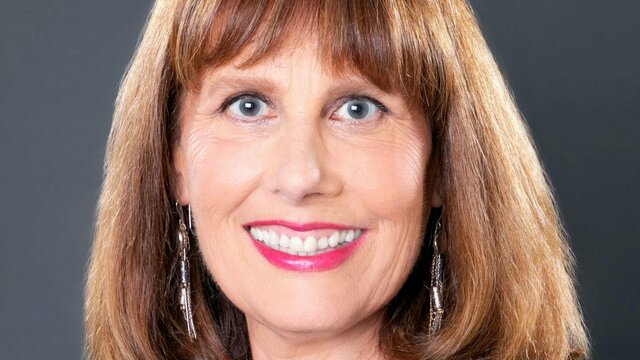 Susannah Fullerton Portrait of a smiling woman with brown hair and long earrings