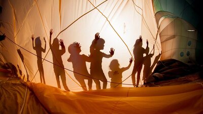 A picture of shadows of children deflating a hot air balloon