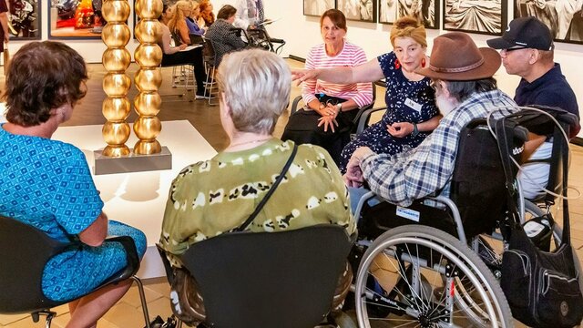 Installation view of Sanné Mestrom, Me & you, 2018 A group of people, some in wheelchairs, sit around a sculpture listening to a guide