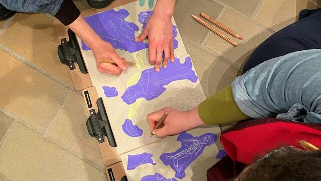 Artmaking in the Art to Wellbeing program An overhead photograph of two people drawing with pencils on brown and purple paper