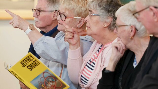 A group of people participating in an Art with Auslan tour A photograph of 5 people in a gallery space pointing and looking forward