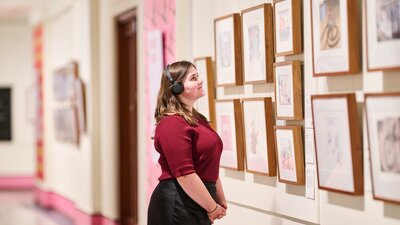 lady wearing headphones looking at photos on a wall