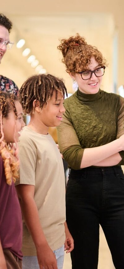 Two children and two adults standing together looking at a picture on the wall