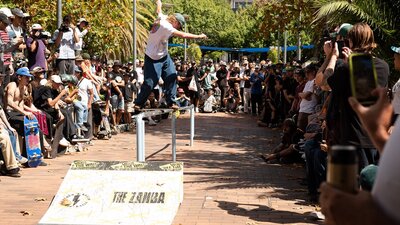 Skateboarder performs Backside Lipslide in front of crowd at Belconnen