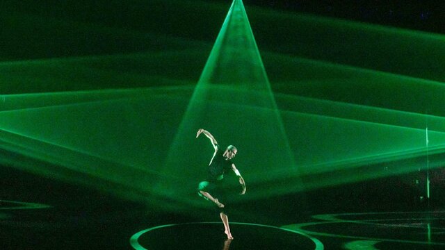 The BOLD Festival A dancer on stage with triangles of bright green light spotlighting