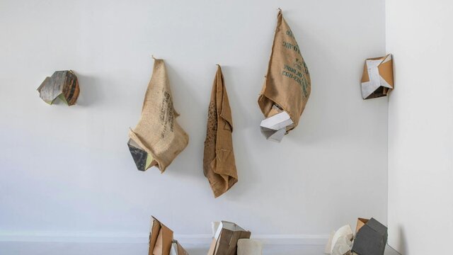 Anie Nheu, 'Between heaven and earth,' 2026. Series of hessian sacks, packaging cardboards, plaster and other materials on a wall.