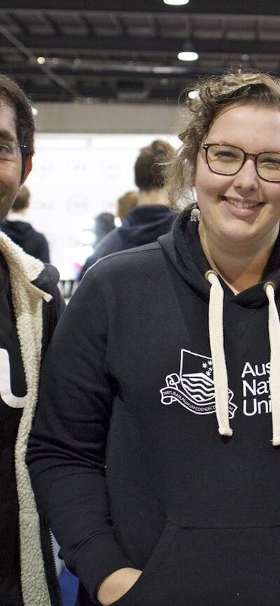 Three staff at the ANU booth smiling.