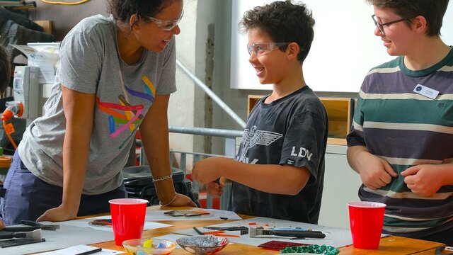 Kilnforming school holiday programs at Canberra Glassworks Participants smiling and cutting glass in Glassworks Engine Room