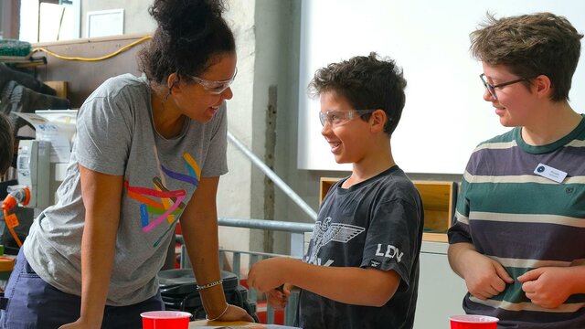 Kilnforming school holiday programs at Canberra Glassworks Participants smiling and cutting glass in Glassworks Engine Room