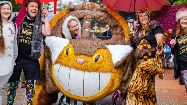 Kinetic Sculpture Race, 2022 People smiling and posing with Cat Bus kinetic sculpture