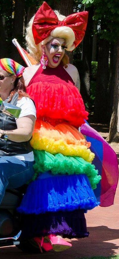 motorbike ridden by woman and drag queen passenger