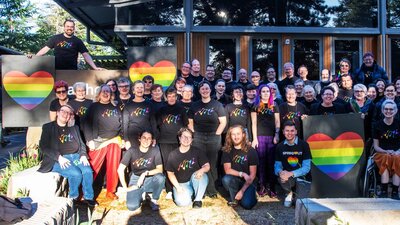 Picture of Canberra QWIRE people smiling and holding rainbow heart banners