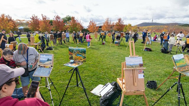 An artist's easel with a fresh artwork an artists easel with an artwork in front of a view of canberra and lake burley griffin