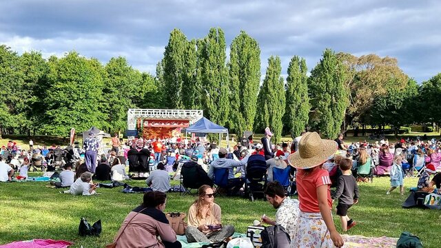 people sitting on a grass field watching Carols in Town Park Canberra
