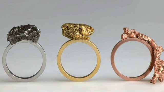 Phoebe Porter | Raw and Refined 2025 Three rings with raw lumps of metal stand upright; one silver, one gold and one copper