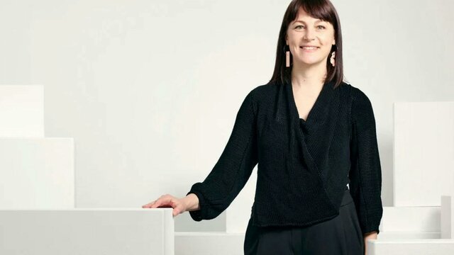 Phoebe Porter Phoebe Porter standing by white plinths and gallery wall smiling