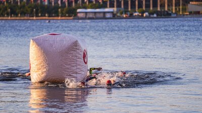 Swimmers swimming around course buoy