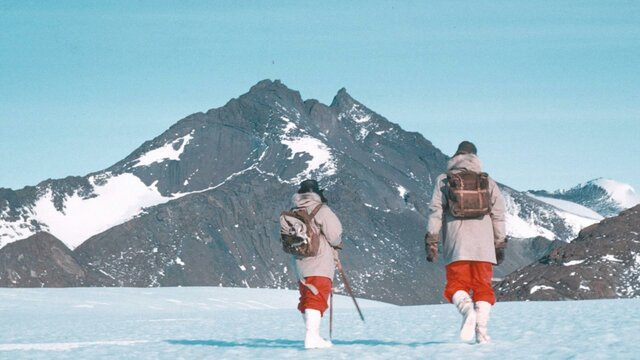 Expeditioners walking towards Mount Henderson, 1960. © George Cresswell/AAD Two hikers walking on snowy ground, in front of snow-covered peaks.