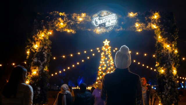Christmas in July Christmas tree Woman standing in front of the festival's entry with Christmas lights and tree