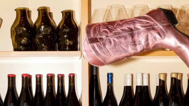 Such and Such A metallic pink cowboy boot sits at a peculiar angle on a shelf full of wine