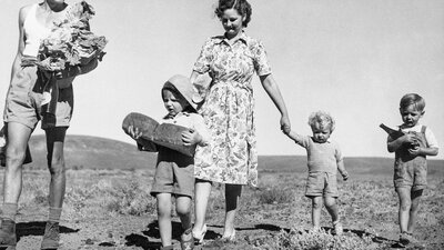 Black and white photograph of a family  with provisions from the tea & Sugar Train