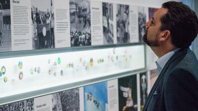 Man looking at exhibition images, text and displayed badges