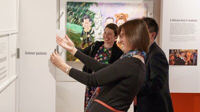Three women opening interactive panels in the exhibition