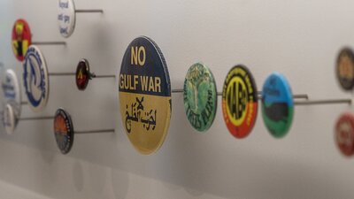 Multiple badges of varying sizes displayed on pins, one says “No Gulf War”