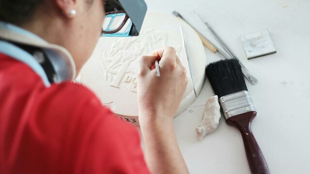 Image of a coin designer sculpting a design on plaster
