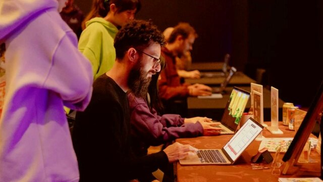Pizza and Pixels Event 2026 A man with a beard sits at a laptop playing a game