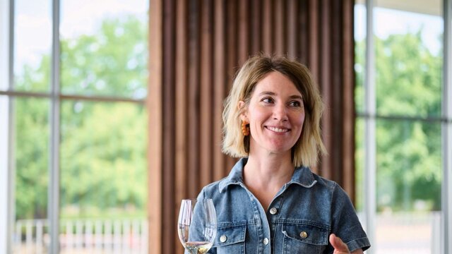 Learn Canberra wine with educator Emma Shaw from Canberra Cellar Door A woman holds a glass of wine and is gesturing with her other hand