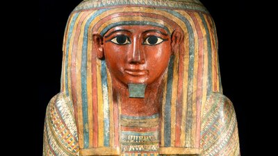 Egyptian wooden coffin of a mela figures with a headdress painted in yellow,  red and blue stripes