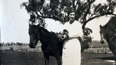 A sepia photograph of a woman with her horses.