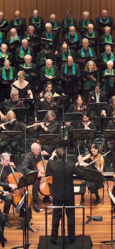 CCS and Llewellyn Choir choristers on Llewellyn Hall stage with 4 soloists, orchestra and conductor