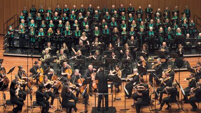 CCS and Llewellyn Choir choristers on Llewellyn Hall stage with 4 soloists, orchestra and conductor