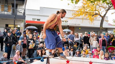 A circus performer walks on a tightrope at low level, in front of a crowd.