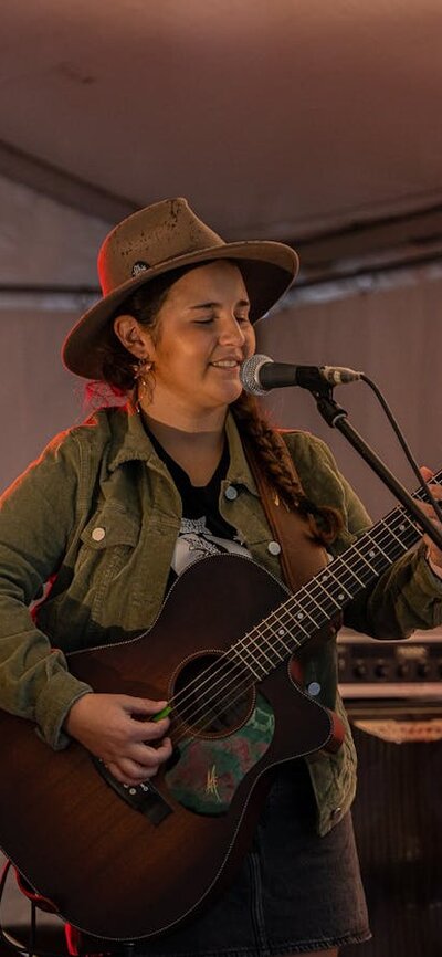 Performer Felicity Dowd, with guitar, singing on stage